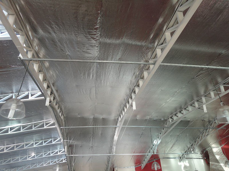Manta térmica instalada sob telhado de pavilhão industrial para amenizar o efeito do calor