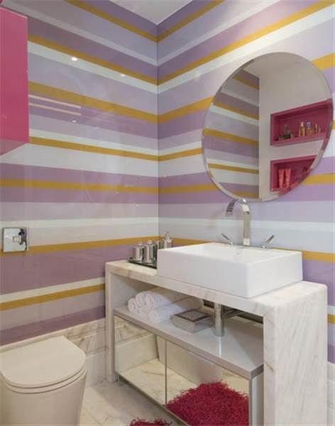 Paredes listradas com cores claras dão toque delicado a decoração desse banheiro super moderno