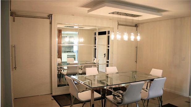 Sala de jantar com mesa de vidro e espelho composto chanfrado decorativo